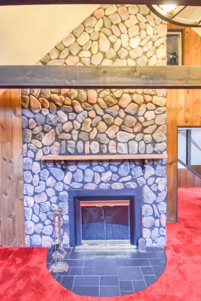 interior details with a stone fireplace, wood walls, and carpet flooring