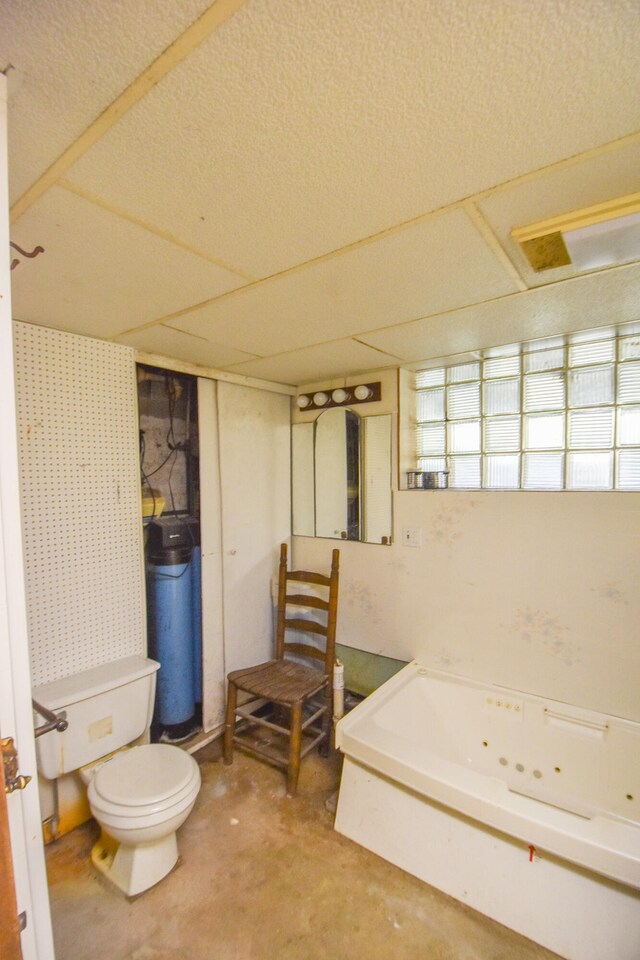 bathroom featuring concrete flooring, a bathtub, and toilet