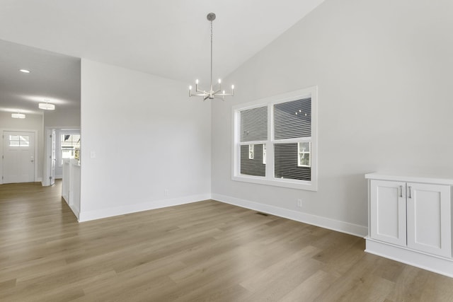 unfurnished room with light wood-type flooring, high vaulted ceiling, and an inviting chandelier