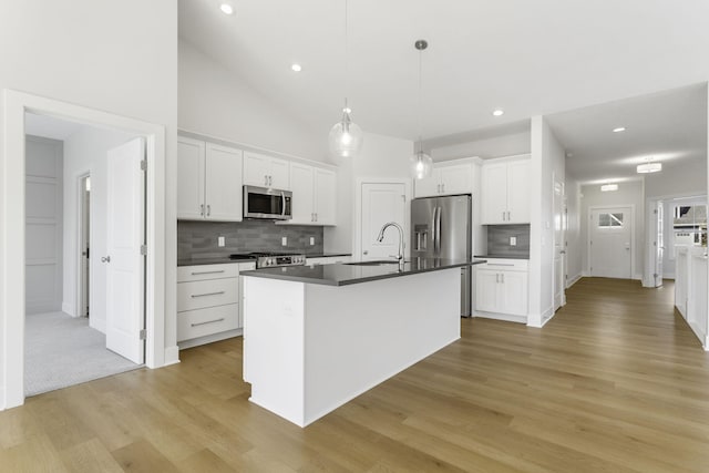 kitchen with pendant lighting, an island with sink, white cabinets, light hardwood / wood-style flooring, and stainless steel appliances