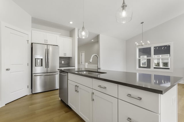 kitchen with an island with sink, sink, hanging light fixtures, white cabinetry, and appliances with stainless steel finishes