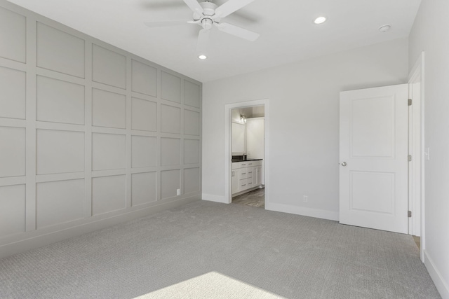 unfurnished bedroom featuring ceiling fan, light colored carpet, and ensuite bath