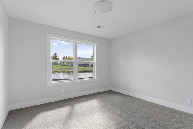 empty room featuring a water view and carpet floors