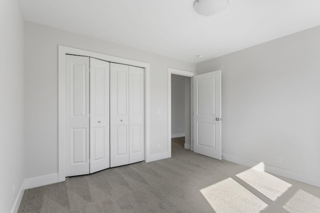 unfurnished bedroom featuring light colored carpet and a closet