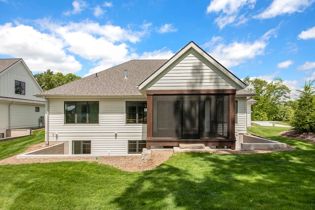 back of house with a sunroom and a lawn