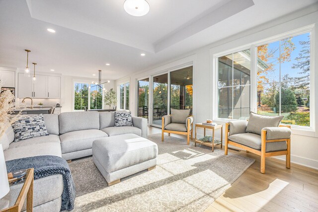 sunroom / solarium with a notable chandelier, a healthy amount of sunlight, sink, and a raised ceiling