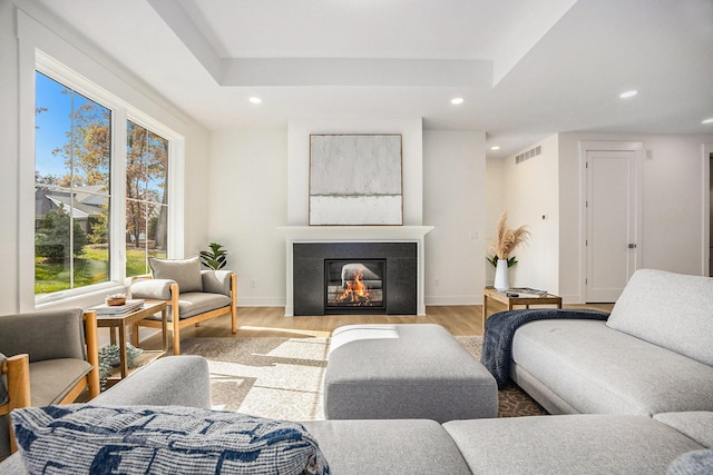 living room featuring visible vents, baseboards, a glass covered fireplace, recessed lighting, and wood finished floors