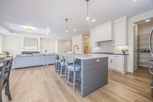 kitchen featuring sink, light hardwood / wood-style flooring, decorative light fixtures, and white cabinets