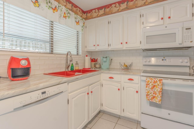 kitchen with backsplash, white appliances, sink, light tile patterned floors, and white cabinets