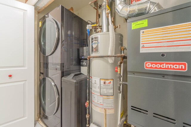 utility room featuring heating unit, stacked washer / dryer, and water heater