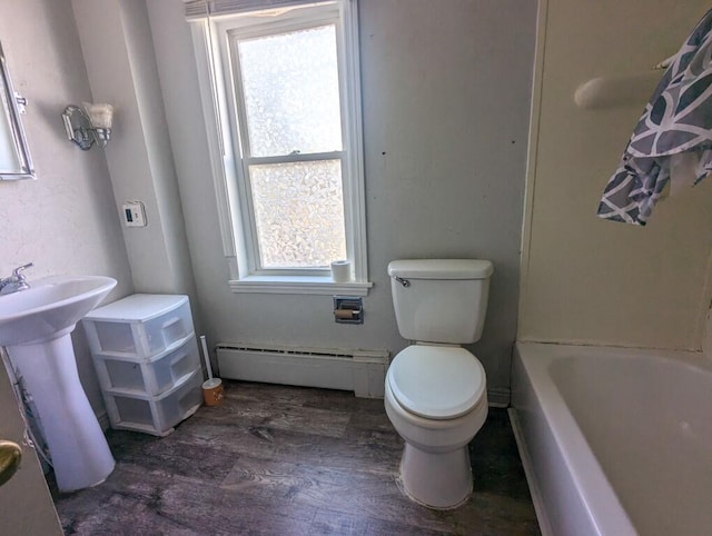 bathroom with wood-type flooring, shower / tub combo, a baseboard heating unit, and toilet