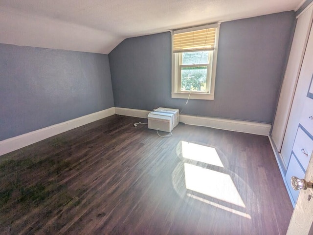 additional living space with a textured ceiling, dark hardwood / wood-style floors, and vaulted ceiling