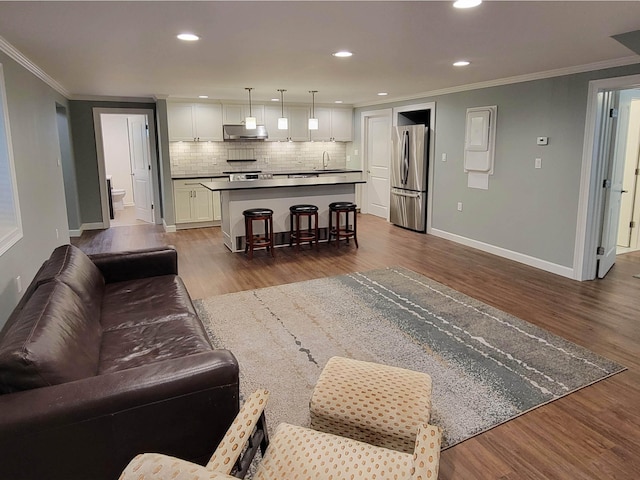 living room with crown molding, sink, and wood-type flooring