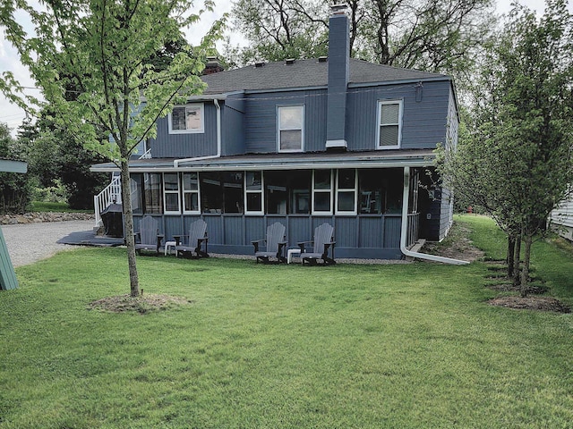 back of property with a sunroom and a lawn