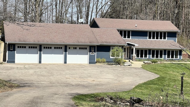 view of front facade featuring a garage, a front lawn, and aphalt driveway