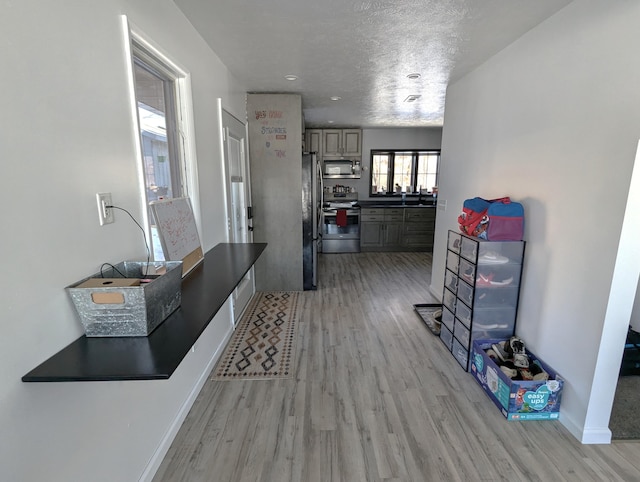 corridor with light hardwood / wood-style floors and a textured ceiling