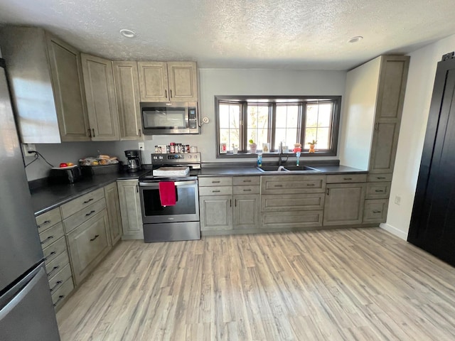 kitchen featuring a textured ceiling, appliances with stainless steel finishes, light hardwood / wood-style floors, and sink