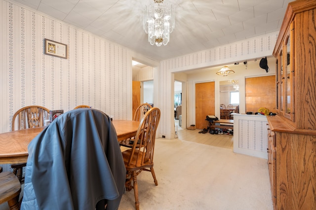 dining room with light carpet and a notable chandelier