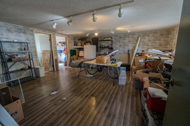 interior space featuring a textured ceiling, dark wood-type flooring, and rail lighting