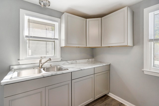 kitchen with dark wood-type flooring, white cabinets, sink, and light stone counters