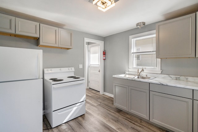 kitchen featuring white appliances, light hardwood / wood-style floors, sink, and gray cabinetry