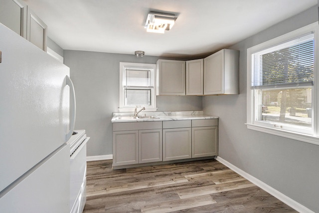 kitchen with light wood-type flooring, sink, and white appliances