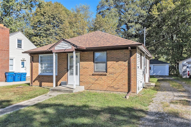 bungalow-style home with a front yard and an outdoor structure