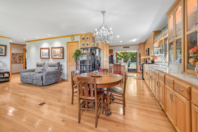 dining room featuring an inviting chandelier, light wood-type flooring, and ornamental molding