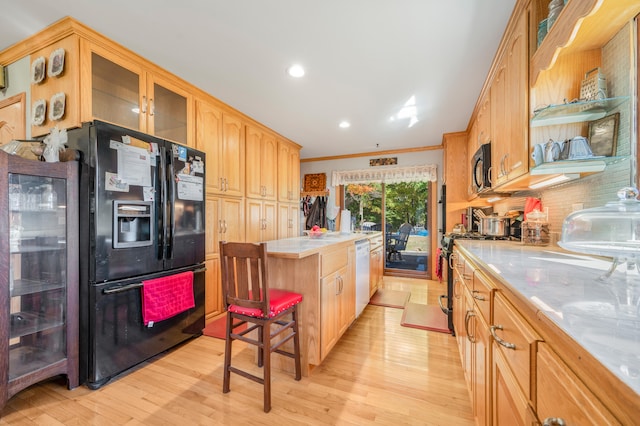 kitchen featuring light wood-type flooring, black appliances, tasteful backsplash, a breakfast bar area, and ornamental molding