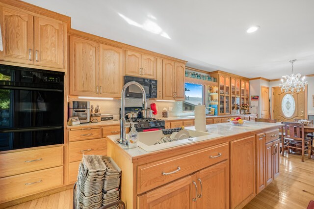 kitchen with tasteful backsplash, light hardwood / wood-style floors, a notable chandelier, and a center island