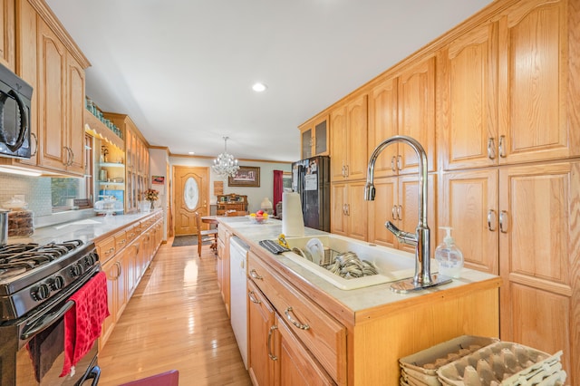 kitchen with black appliances, sink, a chandelier, light hardwood / wood-style flooring, and backsplash