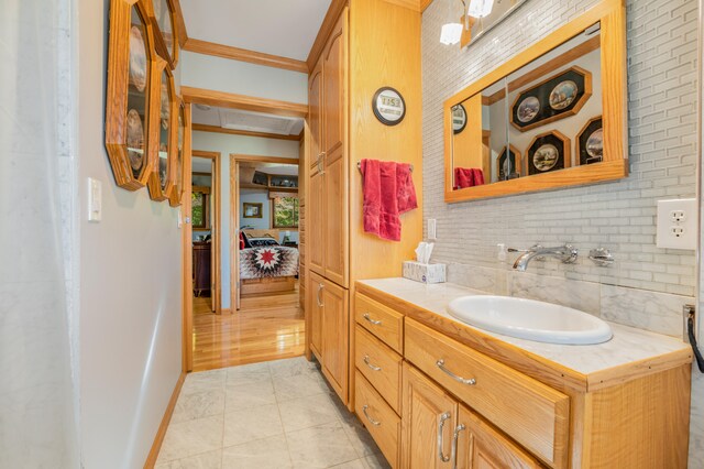 bathroom featuring crown molding, decorative backsplash, vanity, and wood-type flooring