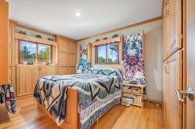 bedroom featuring ornamental molding and light wood-type flooring