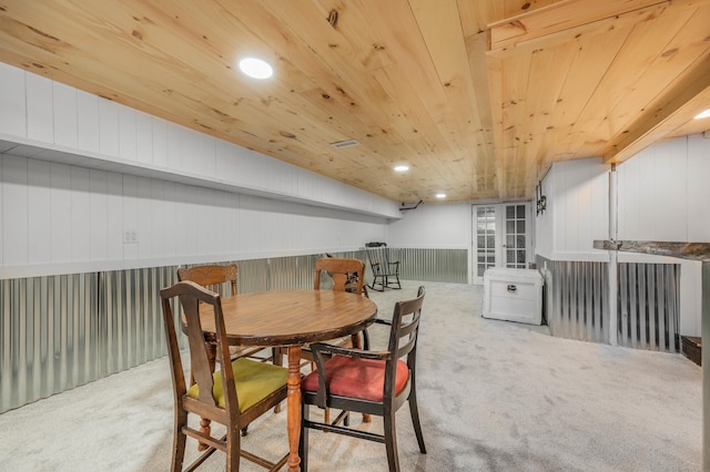 dining space featuring light carpet, wood walls, and wood ceiling