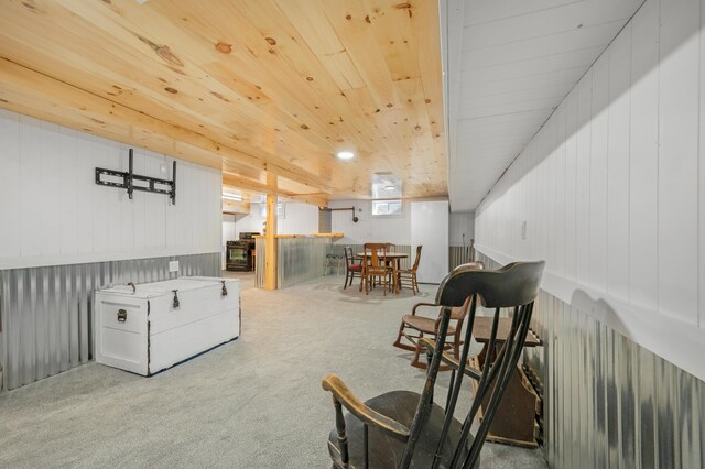 living area featuring light carpet, wood walls, and wooden ceiling