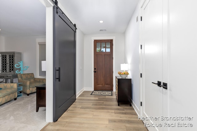 foyer entrance with a barn door and light hardwood / wood-style flooring