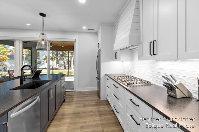 kitchen featuring wood-type flooring, stainless steel appliances, plenty of natural light, and white cabinetry