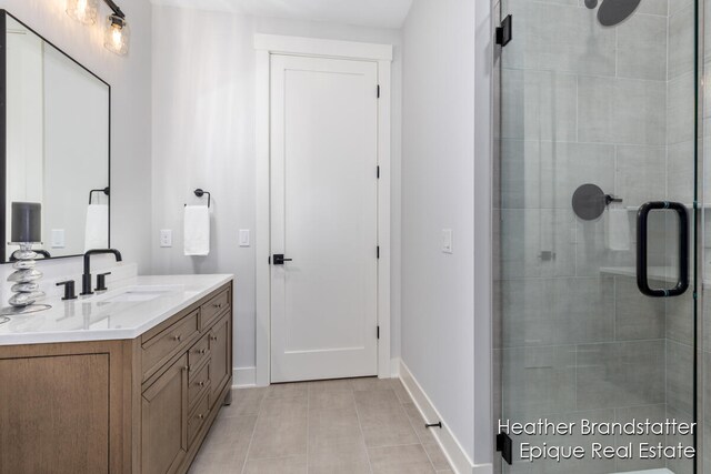 bathroom with walk in shower, vanity, and tile patterned flooring