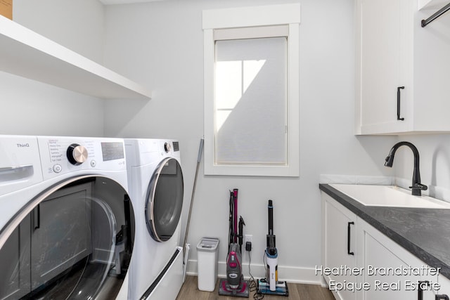 laundry area featuring washer and clothes dryer, cabinets, hardwood / wood-style flooring, and sink