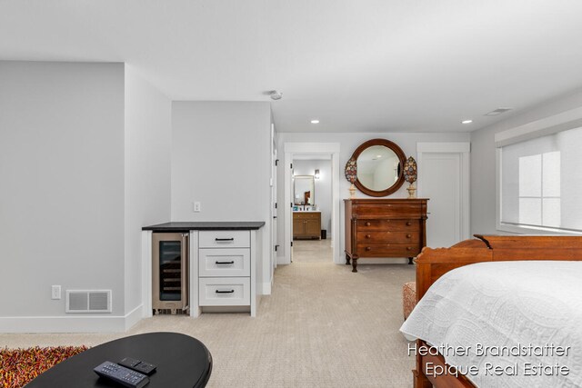 bedroom with light colored carpet, wine cooler, and indoor bar