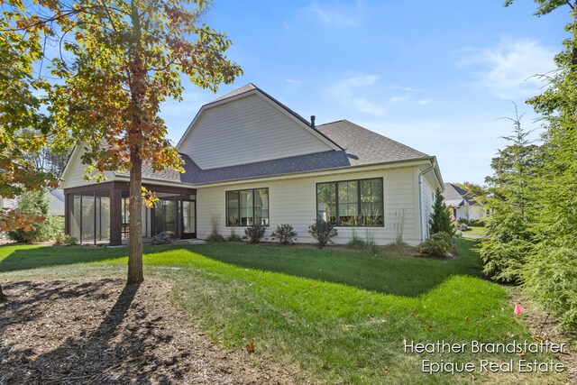 rear view of house featuring a yard and a sunroom