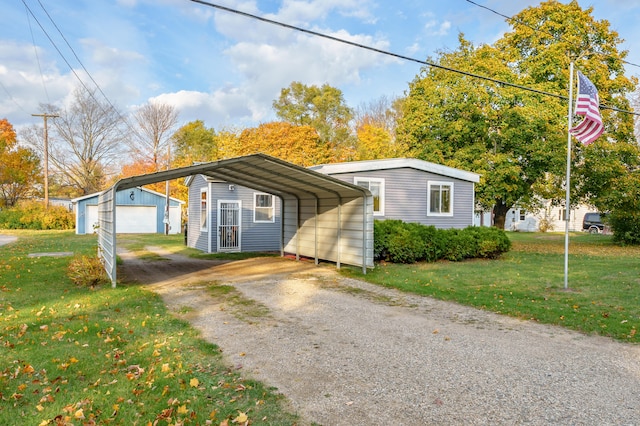 view of front facade with a carport, a garage, a front lawn, and an outdoor structure