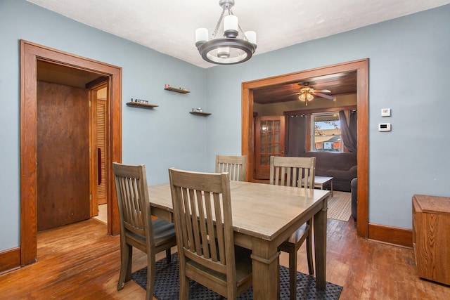 dining space featuring wood-type flooring and ceiling fan with notable chandelier