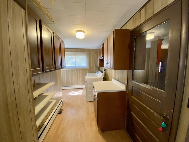 laundry room featuring washing machine and dryer, wooden walls, light hardwood / wood-style floors, and baseboard heating