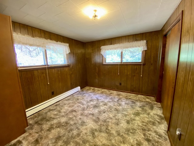 spare room featuring wooden walls, a baseboard radiator, and carpet