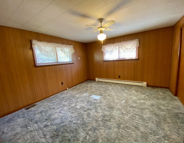 carpeted empty room with ceiling fan, a baseboard radiator, and wood walls