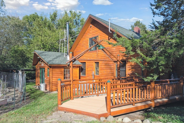 rear view of property featuring a deck and a lawn