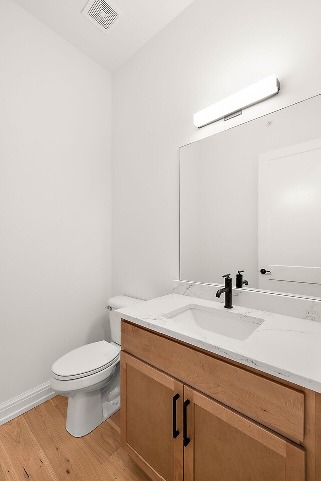 bathroom with vanity, toilet, and hardwood / wood-style floors