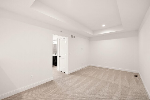 carpeted empty room featuring a raised ceiling