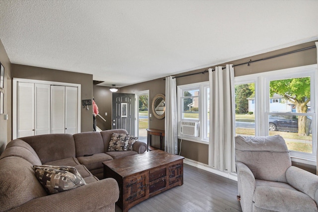 living room featuring cooling unit, hardwood / wood-style flooring, and a textured ceiling